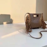 Bolso taupe de mano y bandolera con flecos y tachuelas