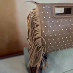 Bolso taupe de mano y bandolera con flecos y tachuelas