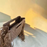 Bolso taupe de mano y bandolera con flecos y tachuelas